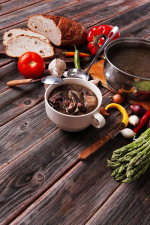 home style beef meat soup vintage country wood table asparagus pepper bell spices bread garlic cutlery eggplantの写真素材
