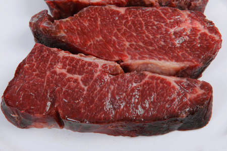 three fresh raw marble beef meat sirloin porterhouse steak on big ceramic cooking pan isolated on white backgroundの写真素材