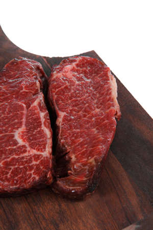 two fresh raw marble beef meat sirloin porterhouse steak on dark wood cut board isolated on white backgroundの写真素材