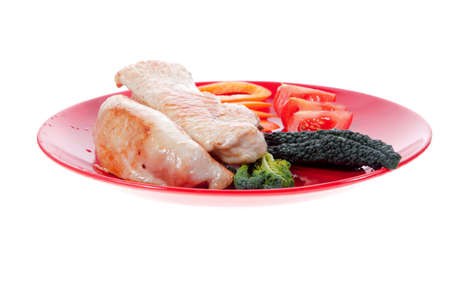 fresh grilled turkey meat fillet steak on red plate with tomatoes pepper green kale and lettuce salad isolated over white backgroundの写真素材