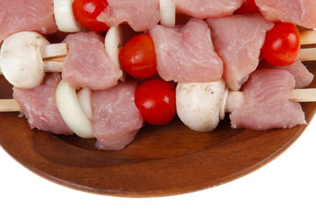 fresh raw meat fillet shish kebab turkey pork pink on skewers tomatoes mushrooms on wooden dish isolated over white backgroundの写真素材