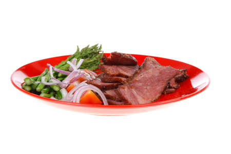 fresh sliced roast beef on red plate with tomatoes and asparagus isolated on white backgroundの写真素材