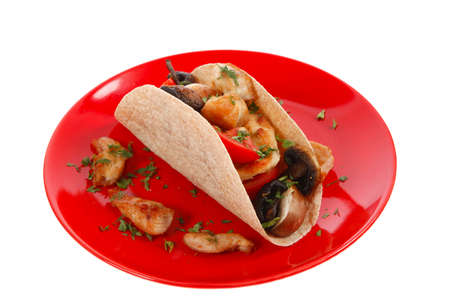 big mexican taco with tomatoes and mushroom on red plate isolated over white backgroundの写真素材