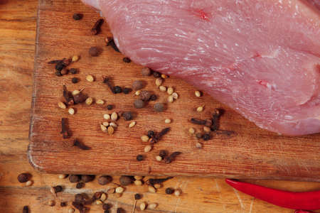 fresh raw turkey meat steak with hot sweet pepper dry spices castor and pepperbox on wood cutting boar over tableの写真素材