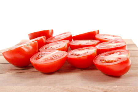 fresh raw tomatoes on light wooden plate isolated over white backgroundの写真素材