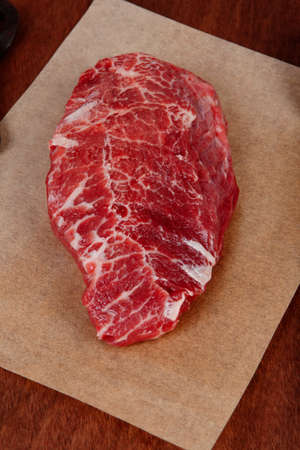 fresh raw beef rib eye steak on walnut table with salt spice and black iron antique forged cutlery fork knifeの写真素材
