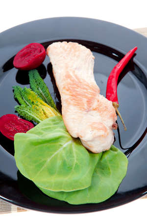 fresh roast turkey meat steak fillet with red hot pepper and green lettuce salad kale on black plate isolated over white backgroundの写真素材