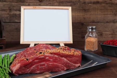 meat raw beef fillet chunk on black tray asparagus on wooden plate allspice pink peppercorn mustard nametable  empty space for textの写真素材