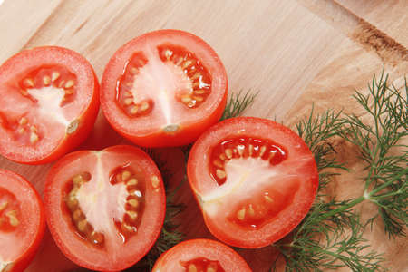 fresh raw tomatoes on light wooden plate isolated over white backgroundの写真素材