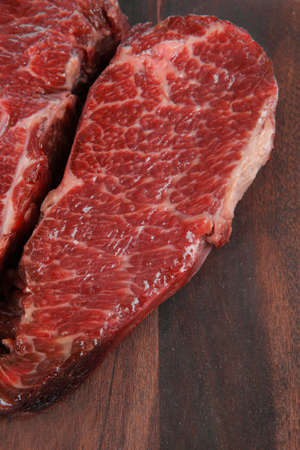two fresh raw marble beef meat sirloin porterhouse steak on dark wood cut board isolated on white backgroundの写真素材