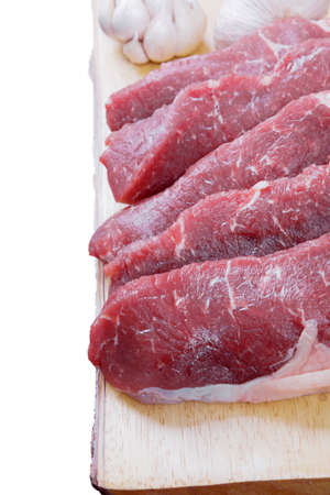 sirloin sinta fillet sliced on wooden plate with garlic and green red hot pepper isolated over white background with white empty menu plate for text nearの写真素材