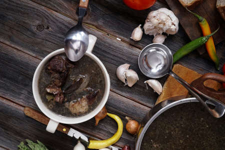 home style beef meat soup vintage country wood table asparagus pepper bell spices bread garlic cutlery eggplantの写真素材