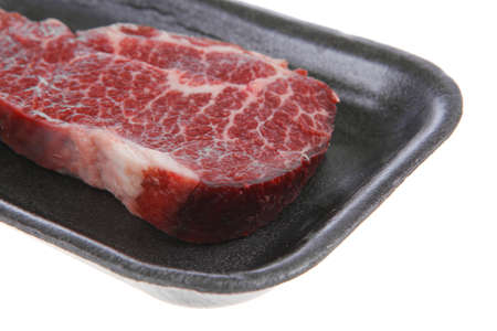 fresh raw marble beef meat steak on black plastic market tray isolated on white backgroundの写真素材
