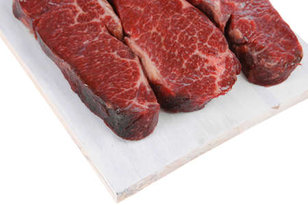 three fresh raw marble beef meat sirloin porterhouse steak on light wood cut board isolated on white backgroundの写真素材