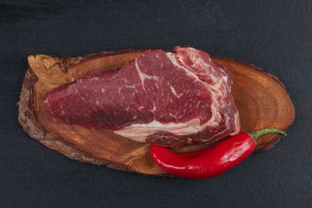 fresh raw piece fillet on small wooden plate with pepper and nameplate space for text on black backgroundの写真素材