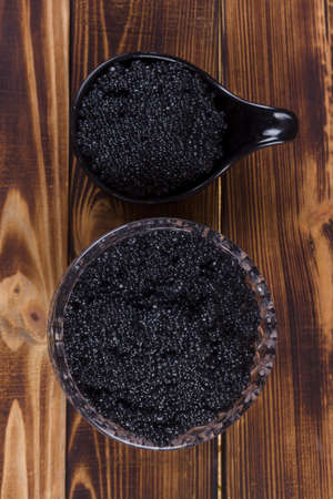 fresh raw black sturgeon hausen caviar in white crystal bowl on wooden backgroundの写真素材