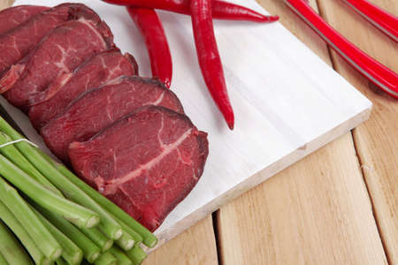 fresh beef meat slices asparagus spices cutlery wooden table pepper hot chili vegetables served garlic light cutting board ready to cookの写真素材