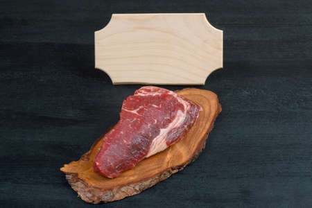 fresh raw piece fillet on small wooden plate with pepper and nameplate space for text on black backgroundの写真素材