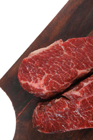 two fresh raw marble beef meat sirloin porterhouse steak on dark wood cut board isolated on white backgroundの写真素材