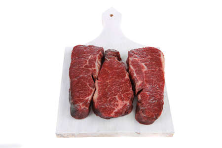 three fresh raw marble beef meat sirloin porterhouse steak on light wood cut board isolated on white backgroundの写真素材