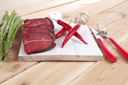 fresh beef meat slices asparagus spices cutlery wooden table pepper hot chili vegetables served garlic light cutting board ready to cookの写真素材