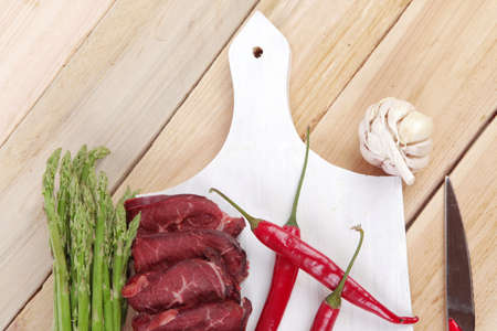 fresh beef meat slices asparagus spices cutlery wooden table pepper hot chili vegetables served garlic light cutting board ready to cookの写真素材
