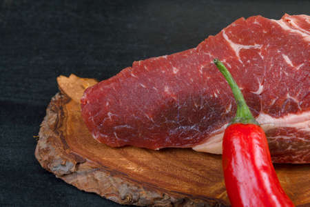 fresh raw piece fillet on small wooden plate with pepper and nameplate space for text on black backgroundの写真素材