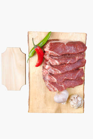 sirloin sinta fillet sliced on wooden plate with garlic and green red hot pepper isolated over white background with white empty menu plate for text nearの写真素材