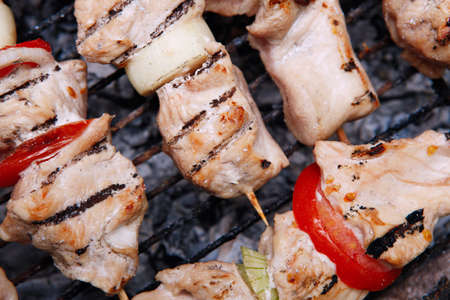 fresh turkey pink brisket shish kebab on wooden skewers with tomatoes over barbecue brazier full burned charcoalの写真素材