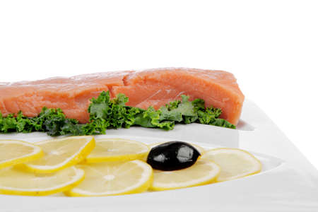healthy food - fresh raw red fish with kale lemon and black olives on plate isolated on white background space for textの写真素材