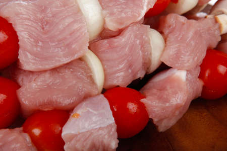 fresh raw meat fillet shish kebab turkey pork pink on skewers tomatoes mushrooms on wooden dish isolated over white backgroundの写真素材