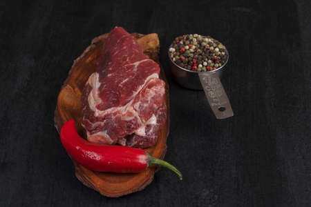 fresh raw beef piece fillet on small wooden plate with pepper peppercorns and nameplate space for text on black backgroundの写真素材