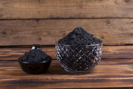 fresh raw black sturgeon hausen caviar in white crystal bowl on wooden backgroundの写真素材
