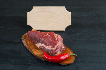 fresh raw piece fillet on small wooden plate with pepper and nameplate space for text on black backgroundの写真素材