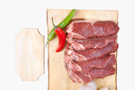 sirloin sinta fillet sliced on wooden plate with garlic and green red hot pepper isolated over white background with white empty menu plate for text nearの写真素材