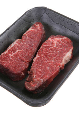 two fresh raw marble beef meat sirloin porterhouse steak on black market plastic tray isolated on white backgroundの写真素材