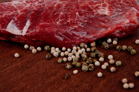 fresh raw beef meat steak with white and green peppercorn spice on walnut tableの写真素材