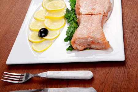 healthy food fresh roast red fish salmon with kale lemon antipesto ketchup sauce on white plate over wooden tableの写真素材