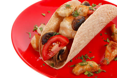 big mexican taco with tomatoes and mushroom on red plate isolated over white backgroundの写真素材