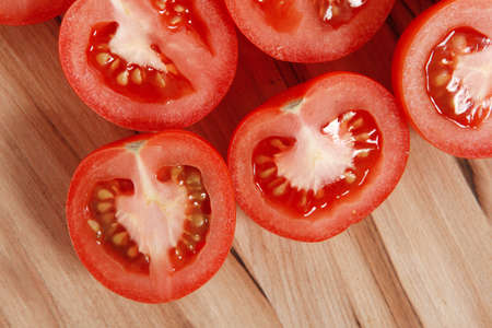 fresh raw tomatoes on light wooden plate isolated over white backgroundの写真素材