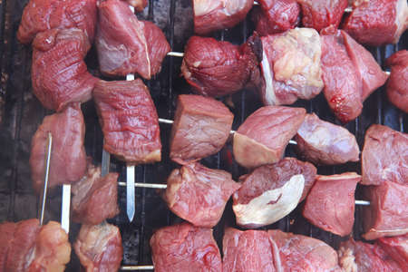 fresh raw turkey fillet steak red meat brisket on skewers barbecue brazier grid full burned charcoalの写真素材