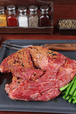 meat raw beef fillet chunk on black tray asparagus on wooden table allspice pink white black green peppercornの写真素材