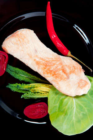 fresh roast turkey meat steak fillet with red hot pepper and green lettuce salad kale on black plate isolated over white backgroundの写真素材