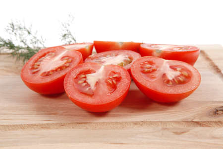 fresh raw tomatoes on light wooden plate isolated over white backgroundの写真素材
