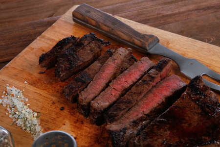 fresh roast red beef meat fillet mignon cutted on wooden plate with vintage fork many different kinds of dry spice over tableの写真素材