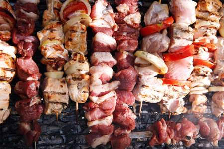 fresh raw beef fillet steak red meat and white chicken brisket on skewers barbecue brazier grid full burned charcoalの写真素材