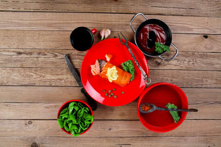 delicious portion of fresh roast salmon fillet on red plate with green salad kale tomato soup bbq sauce and black coffee over wooden table - healthy food, diet cooking concept kale tomato soup bbq sauce and black coffee over wooden table - healthy food, diet cooking conceptの写真素材