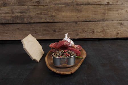 fresh raw beef piece fillet on middle size wooden plate with pepper and peppercorns in measuring spoon with name plate space for text on black backgroundの写真素材