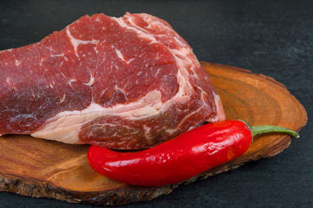 fresh raw piece fillet on small wooden plate with pepper and nameplate space for text on black backgroundの写真素材