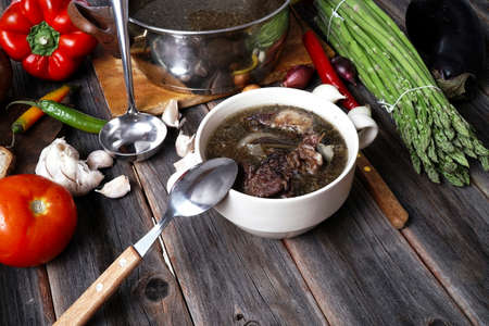 home style beef meat soup vintage country wood table asparagus pepper bell spices bread garlic cutlery eggplantの写真素材